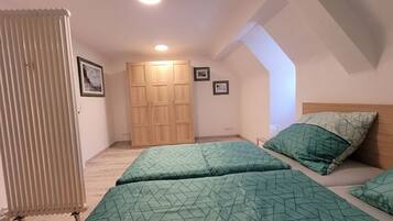 Ein Schlafzimmer mit zwei Betten, einem Holzschrank und einer schrägen Decke.
