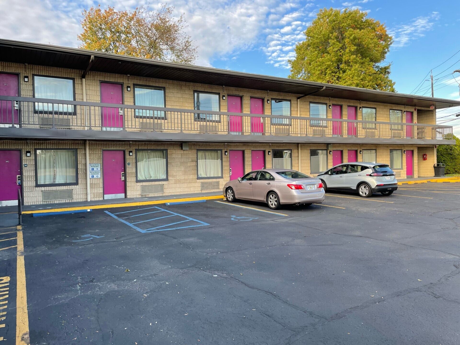 A motel with two-story buildings, parking spaces, and a clear sky.