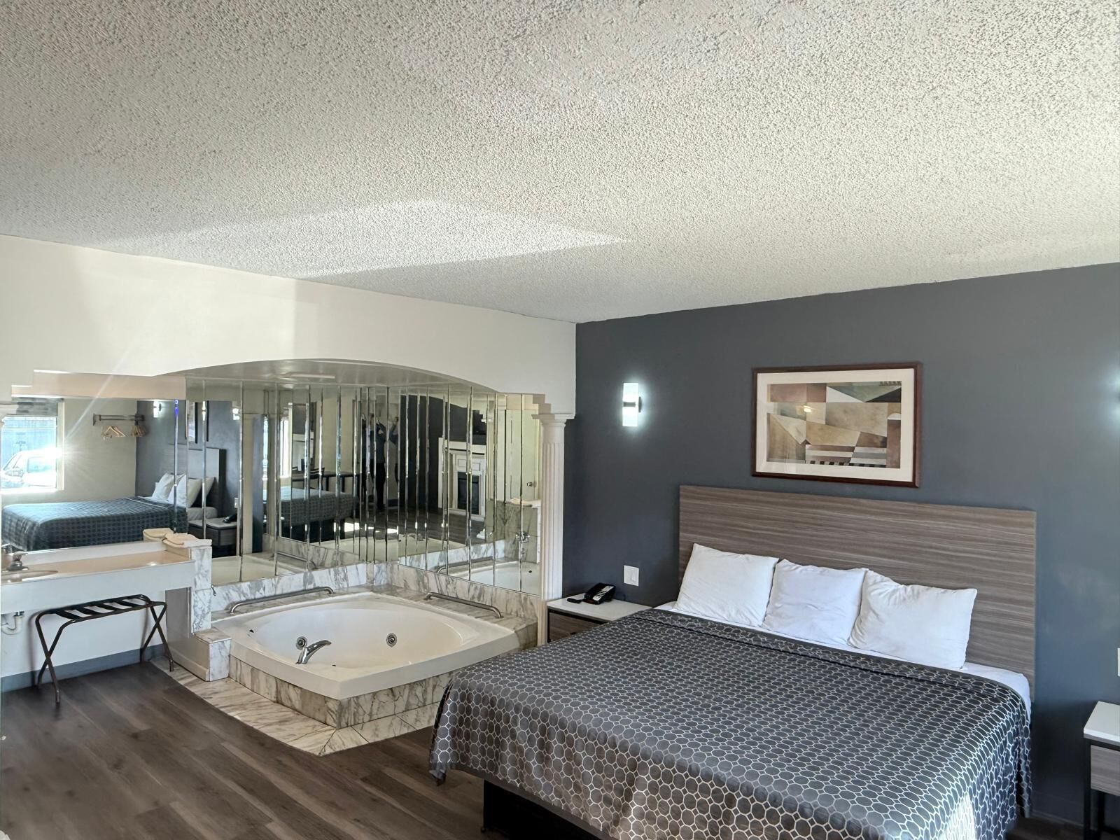 A modern hotel room with a large bed, a separate bathroom with a bathtub, and a glass-enclosed shower area.