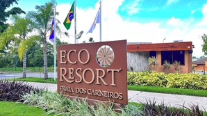 Un letrero de ECO RESORT con un edificio moderno al fondo.
