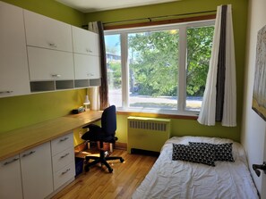 Cozy retreat with a single bed, desk, and window view of the outdoors.