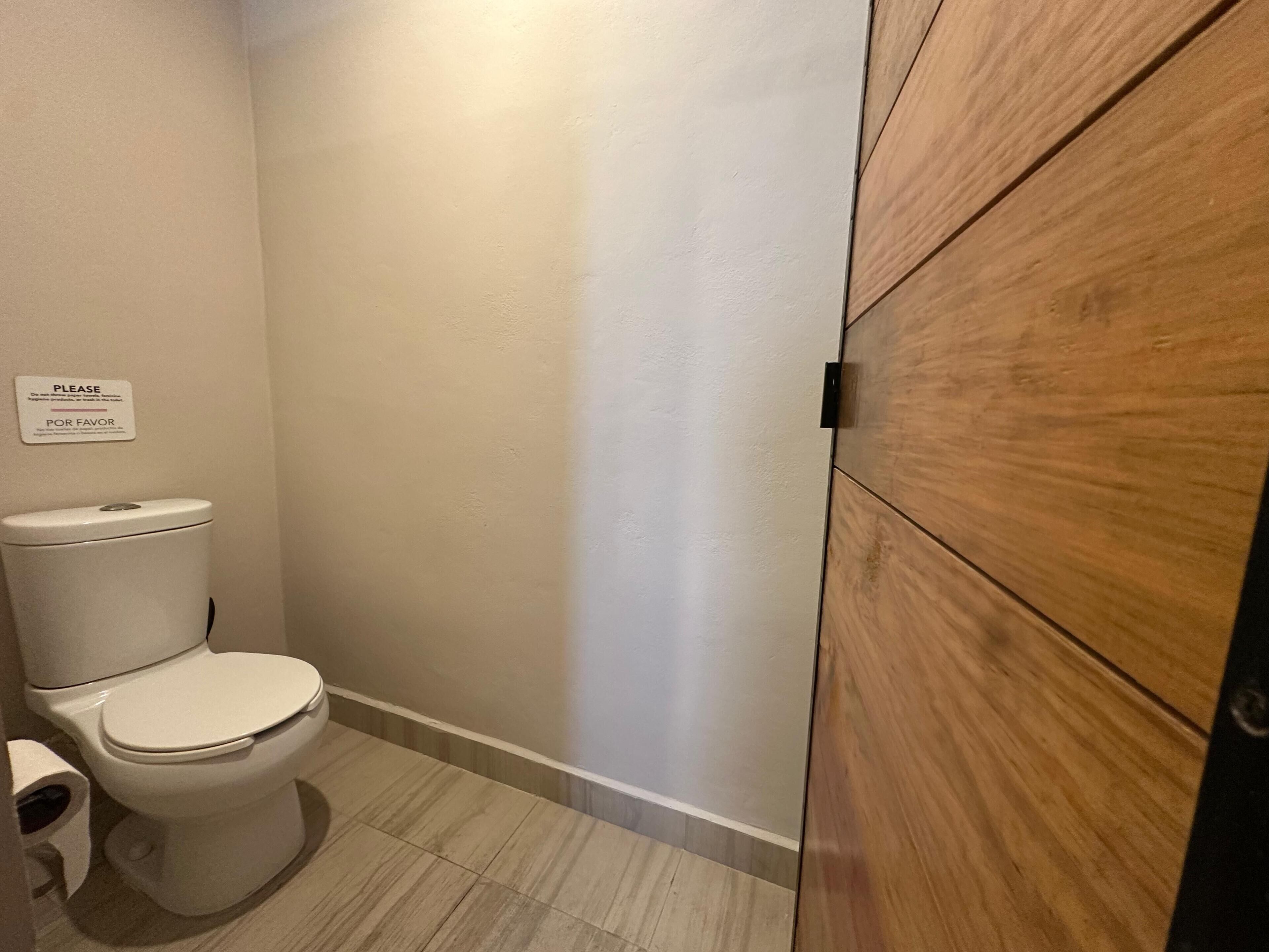 Ein kleines, sauberes Badezimmer mit Toilette, einem Holzschrank und einem Schild an der Wand.