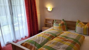 A hotel room with a bed, a nightstand, a lamp, and a window with curtains. - Christians Hamat by Interhome (Ischgl)