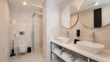 A modern bathroom with a glass shower enclosure, a white sink, and two large mirrors.
