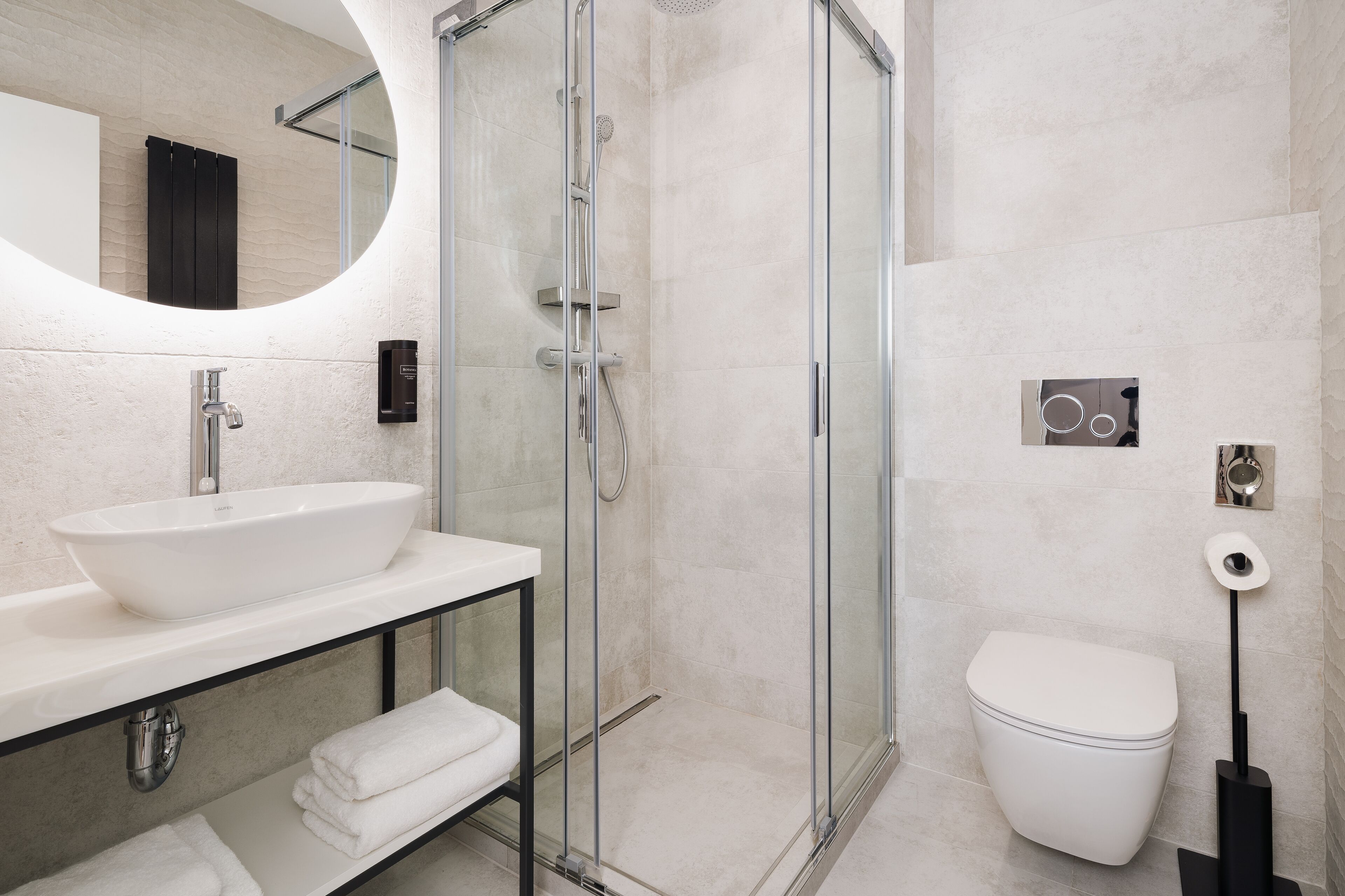 A modern bathroom with a glass-enclosed shower, a white sink, and a toilet.
