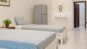 A bedroom with two beds, a grey wardrobe, a small table with a plant, and a framed picture on the wall. - Luxurious Chalet in Porto Said With Beachfront View View (Al-Manasrah)