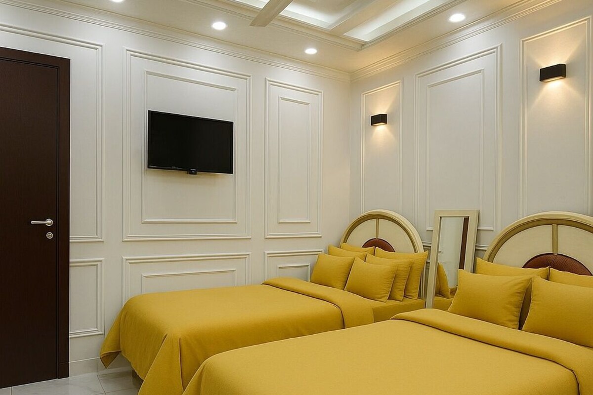 A hotel room with two beds, a ceiling fan, recessed lighting, a flat-screen TV, and a door.