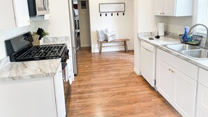 Une cuisine moderne avec des armoires blanches, une cuisinière noire et un plancher en bois.