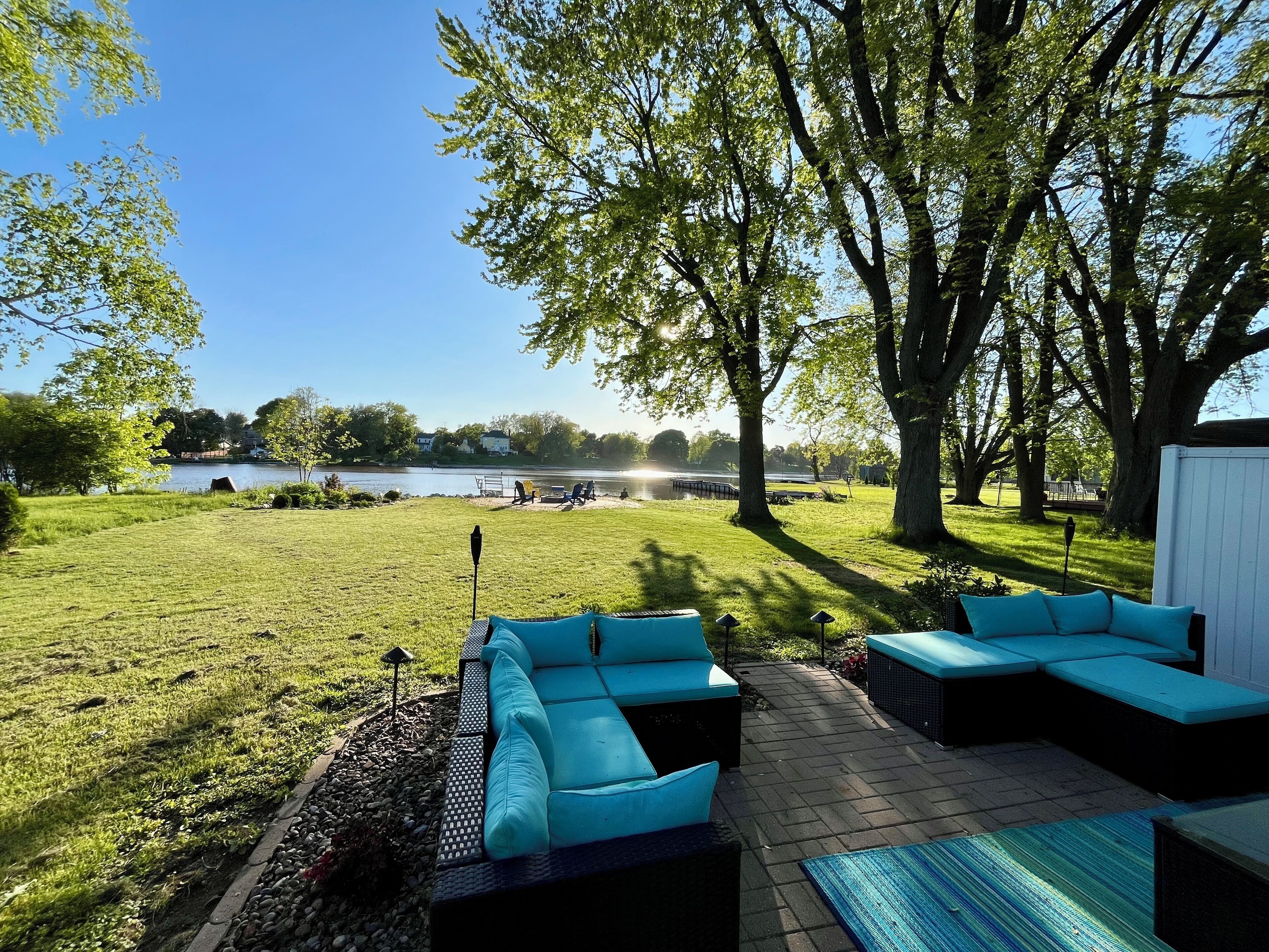 A patio with outdoor furniture, a view of a lake, and trees.