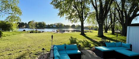 A patio with outdoor furniture, a view of a lake, and trees.
