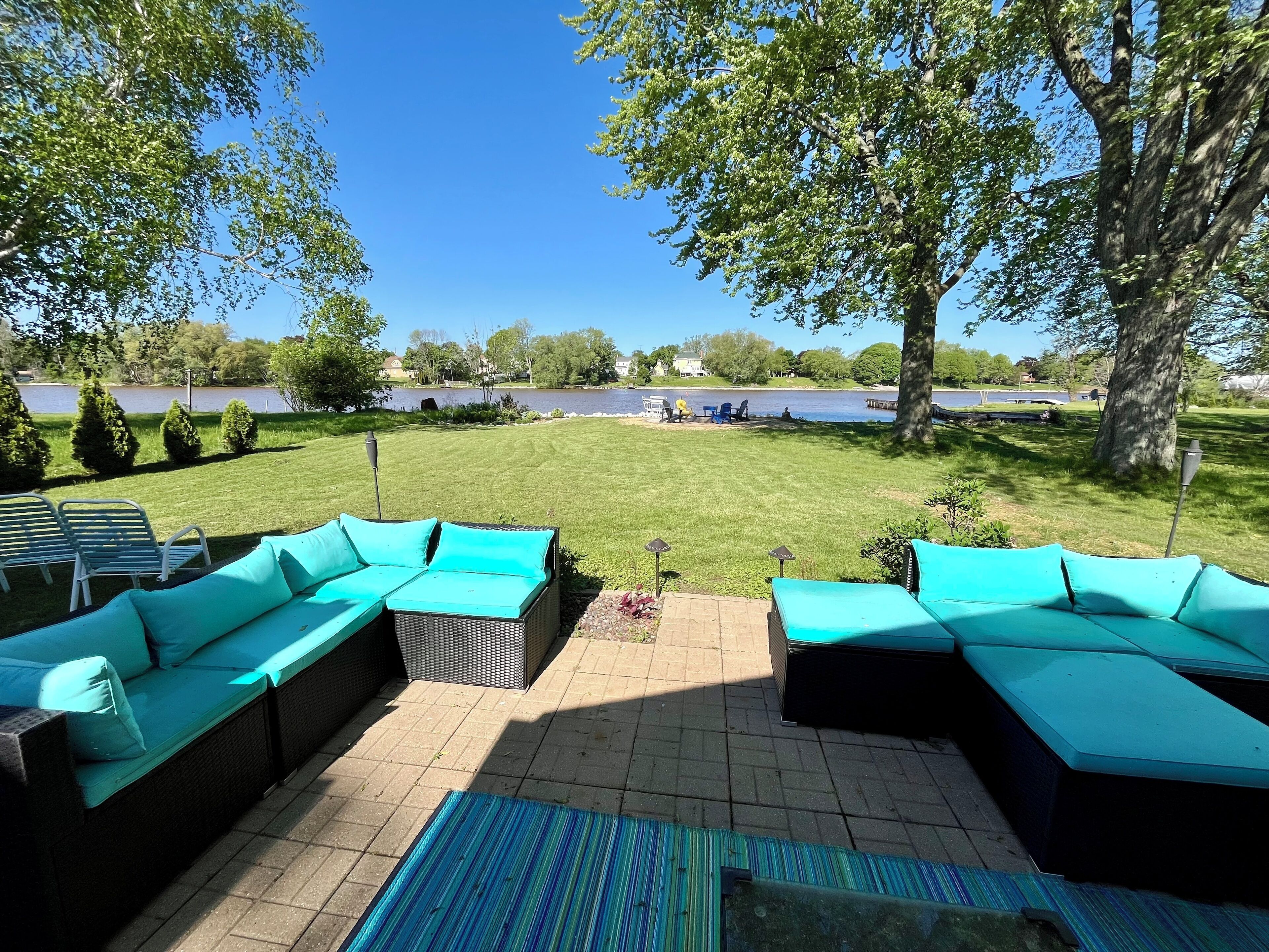 A patio with a sectional sofa and a view of a lake.