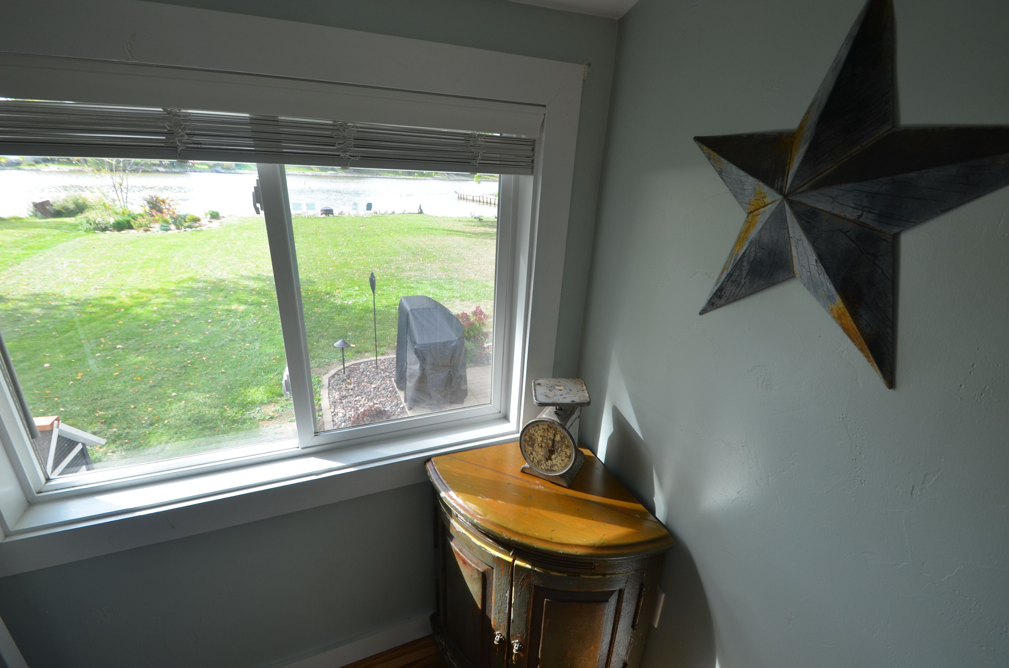 A room with a large window, a star decoration on the wall, and a vintage scale on a wooden table.