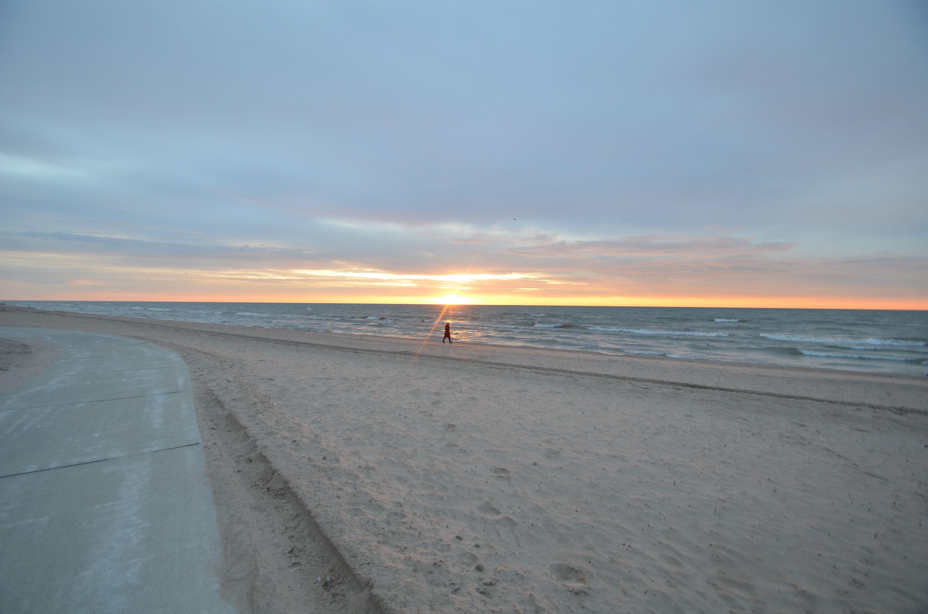 A beach with a concrete path and ocean view.