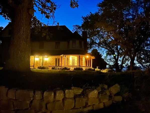 A stone wall in front of a house at dusk. - A spacious finely-appointed luxury hideaway, nestled in the Ozark Mountains. (Lebanon)