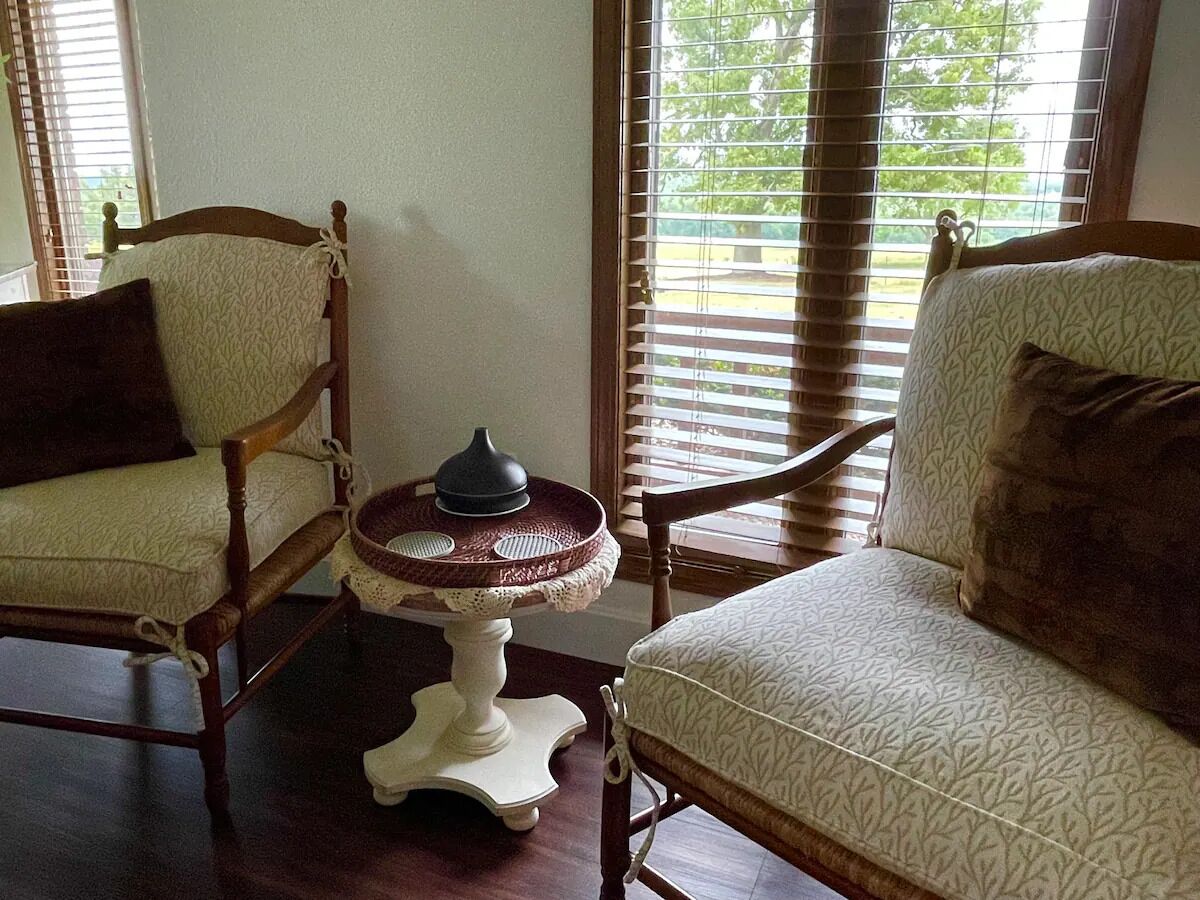 A room with two wooden chairs and a small white table with a decorative item on it.