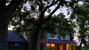 A two-story house with a porch, surrounded by trees and a well-maintained lawn. - A spacious finely-appointed luxury hideaway, nestled in the Ozark Mountains. (Lebanon)