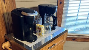 Una encimera de cocina con una cafetera, un molinillo de café y una caja de cápsulas de café.