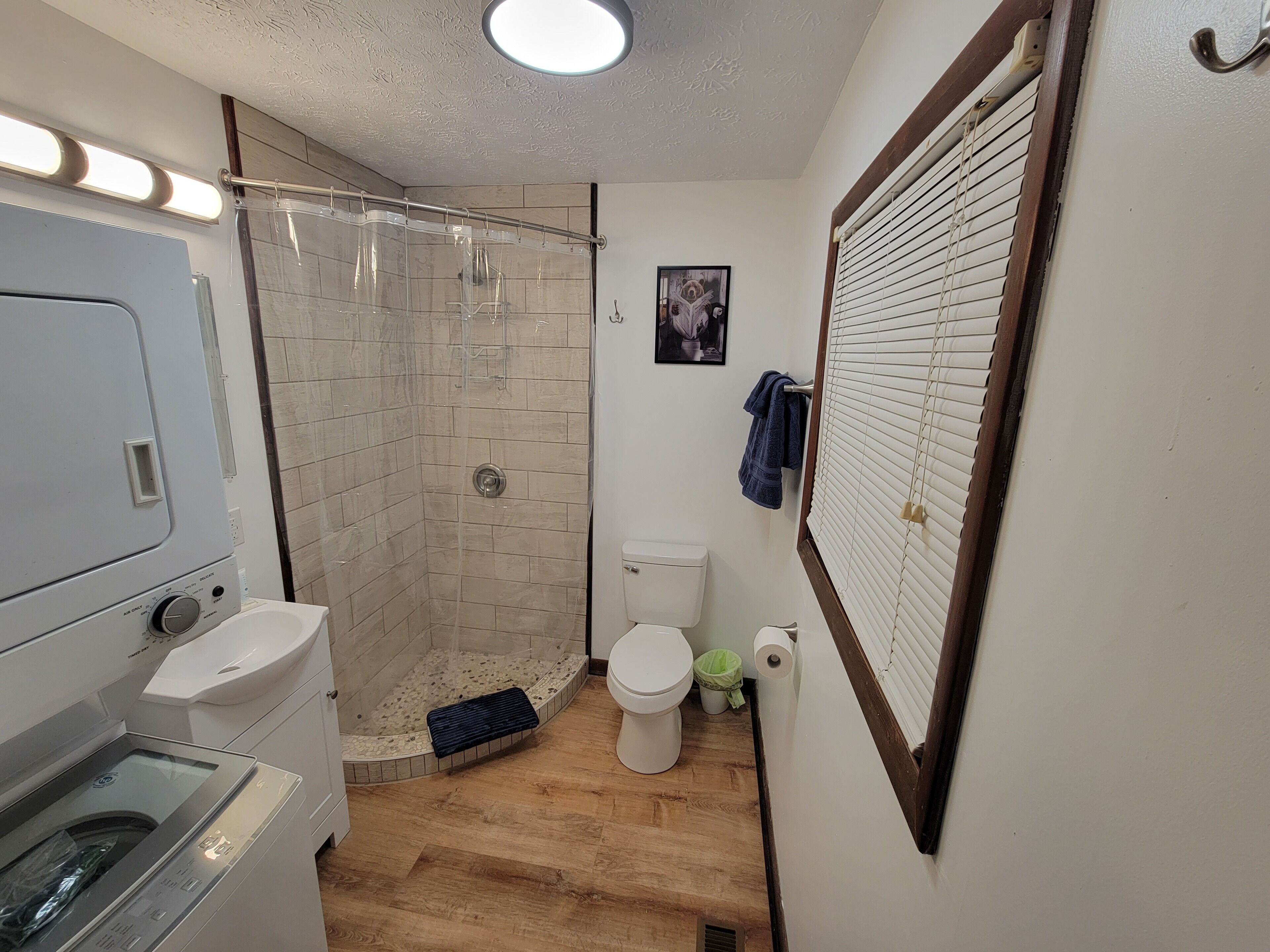 A bathroom with a shower, toilet, and a washing machine.
