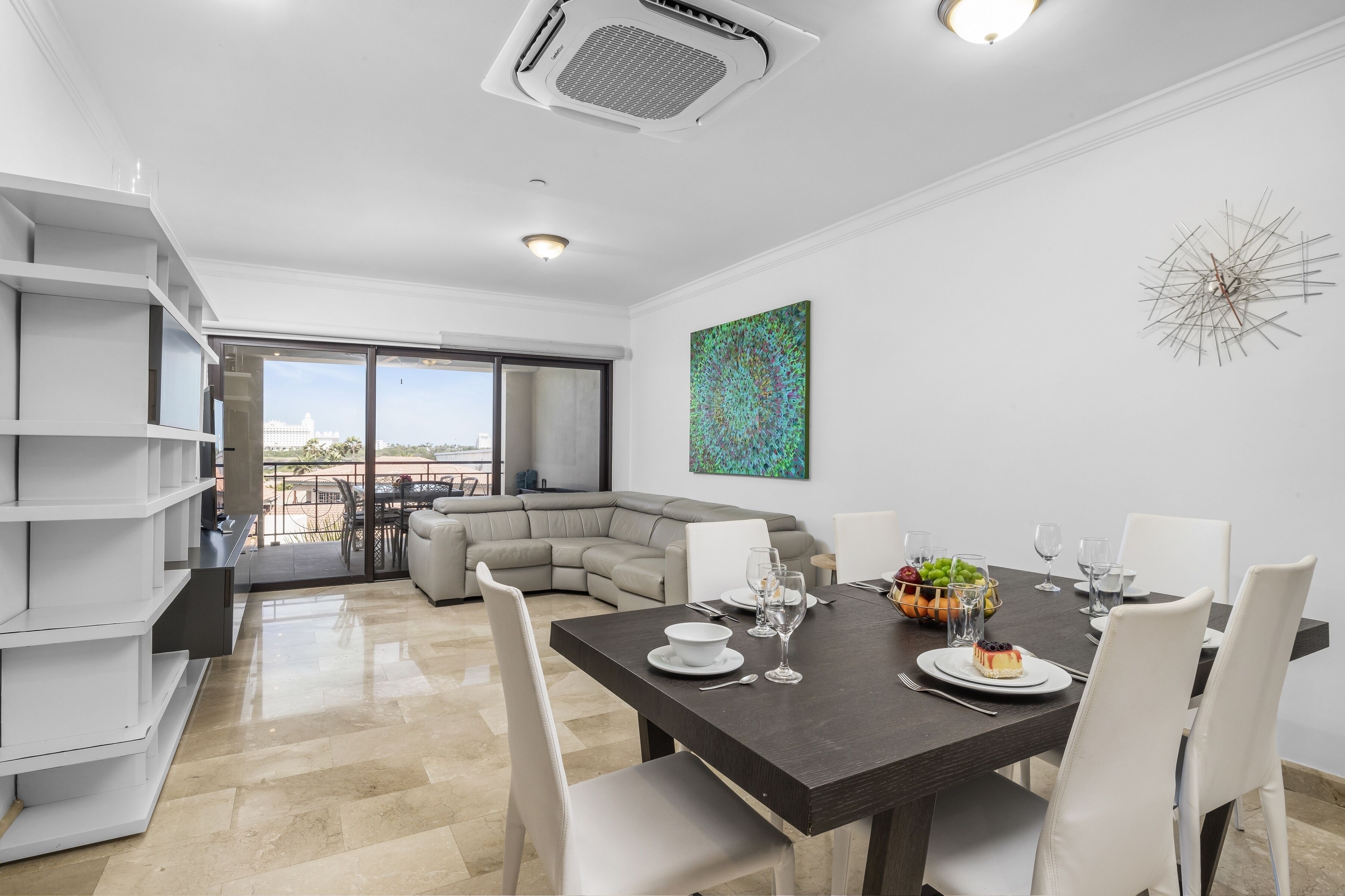 A modern living room with a dining area, a large window, and a view of a building.