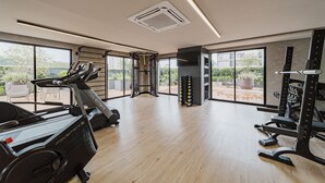 Une salle de sport moderne, équipée de matériel d’exercice, dotée de grandes fenêtres et offrant une vue sur l’extérieur.