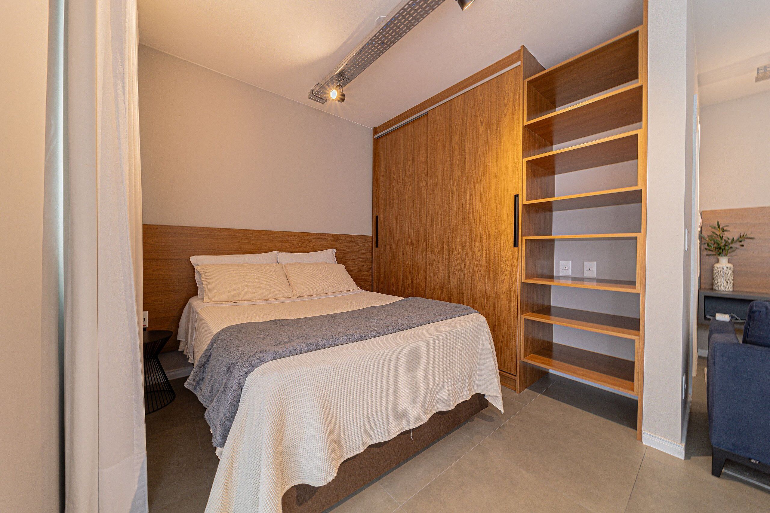 A bedroom with a bed, wooden wardrobe, and a desk.