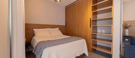 A bedroom with a bed, wooden wardrobe, and a desk.