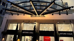 A multi-story building with a modern architectural design, featuring a glass atrium with string lights, and storefronts labeled "ARTURO CALLE" with a sale sign. - Modern, Cozy Apartment with Air Conditioning Encanto Cayala, Steps from Cayala (Ciudad de Guatemala)