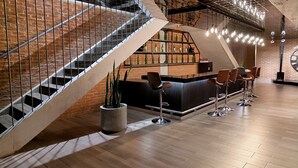 A modern bar area with a staircase, wooden flooring, and bar stools. - Modern, Cozy Apartment with Air Conditioning Encanto Cayala, Steps from Cayala (Ciudad de Guatemala)