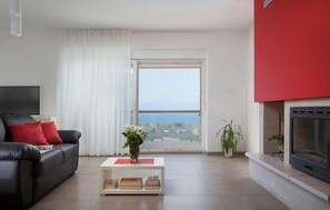 Relax in this stylish living room with a sofa, coffee table, and fireplace, offering a view of the sea.