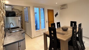 A modern kitchen with a built-in sink and a dining area with a wooden table and black chairs. - Lélégance de la Pierre (Fourques)
