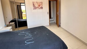 A bedroom with a large bed, a wardrobe, a mirror, and a door leading to another room. - Lélégance de la Pierre (Fourques)