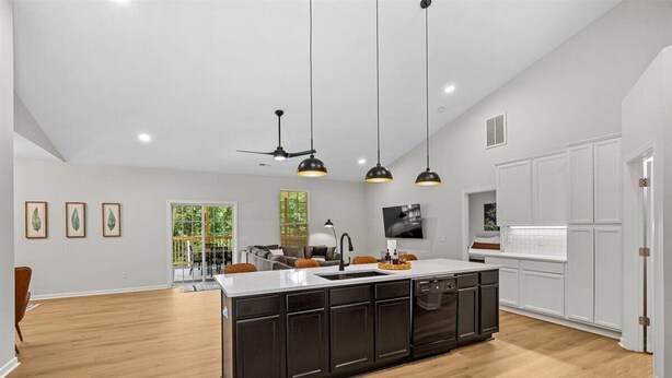 Cocina moderna con muebles oscuros, una isla central e iluminación colgante.