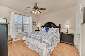 A bedroom with a bed, two bedside tables with lamps, a ceiling fan, a window with blinds, and a chair. - Gorgeous, Spacious Condo With Balcony (Davenport)