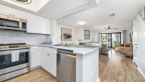 A modern kitchen with white cabinetry, stainless steel appliances, and a central island.