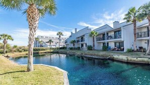 A residential area with a swimming pool, palm trees, and modern houses with balconies.