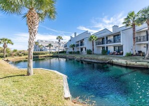 Stunning water feature surrounded by lush greenery and palm trees, set amidst a contemporary residential complex with balconies and outdoor seating areas.