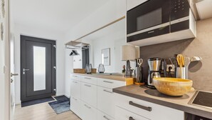 A modern kitchen with white cabinets, a black microwave, and a coffee maker. - GebirgsResort Winterberg 123 (Winterberg)