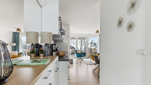 A modern kitchen with white cabinets, a wooden countertop, and a view to the living area. - GebirgsResort Winterberg 123 (Winterberg)