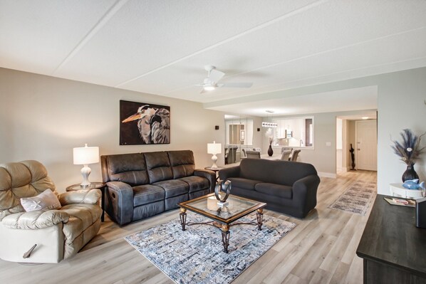 A modern living room with a leather sofa, a glass coffee table, and a painting on the wall. - Heron's Nest (St. Augustine)