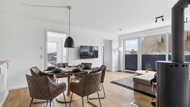 A modern dining area with a round table, quilted chairs, and a television above. - GebirgsResort Winterberg (Winterberg)