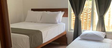 Una habitación con dos camas, una ventana con cortinas y una puerta.