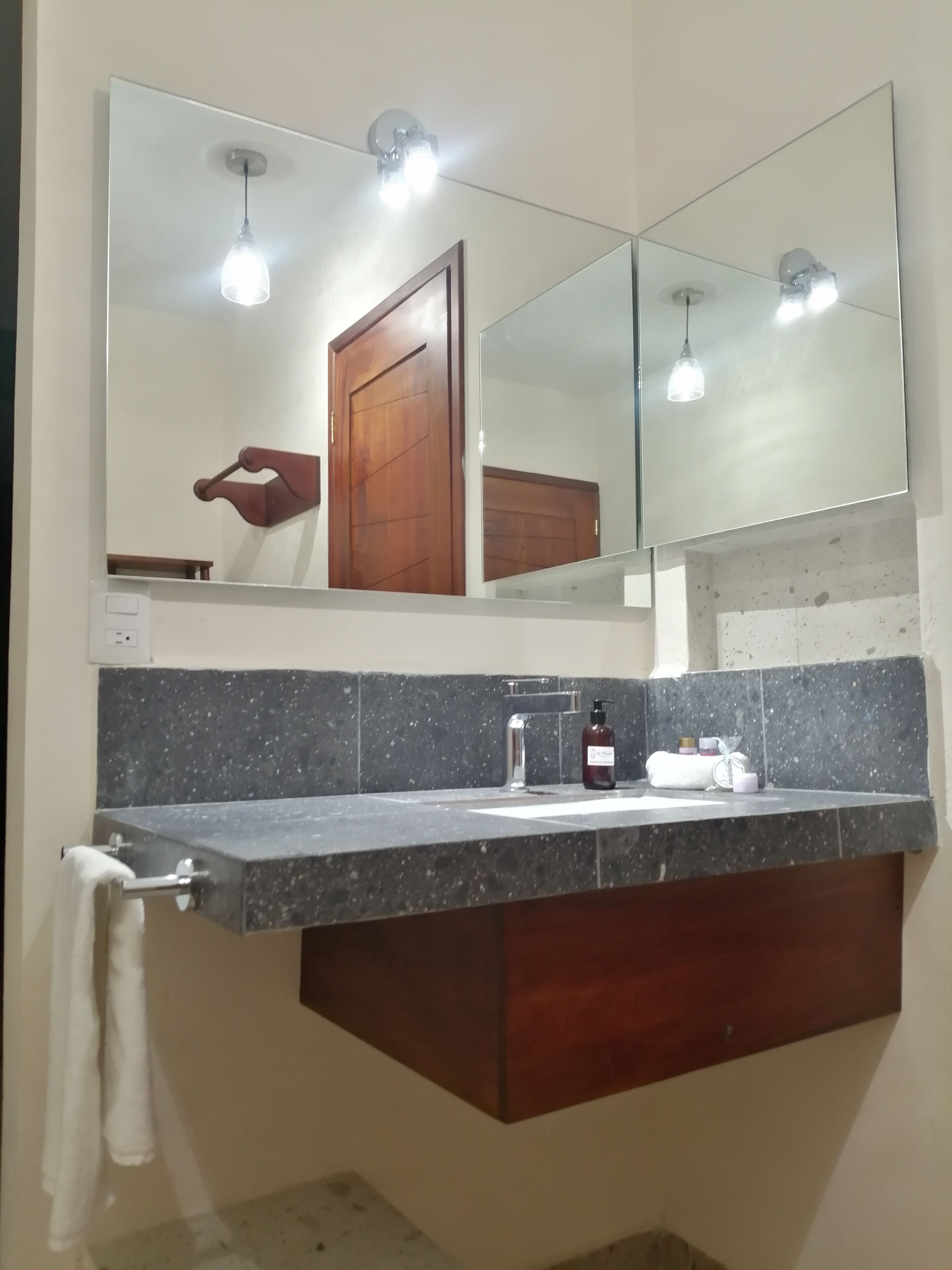 A bathroom with a granite countertop, a sink, a mirror, and a towel rack.