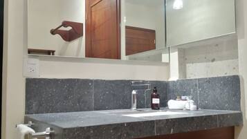 A bathroom with a granite countertop, a sink, a mirror, and a towel rack.