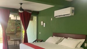 Een slaapkamer met een groot bed, een plafondventilator, een airconditioning en uitzicht op de omgeving door een glazen deur.