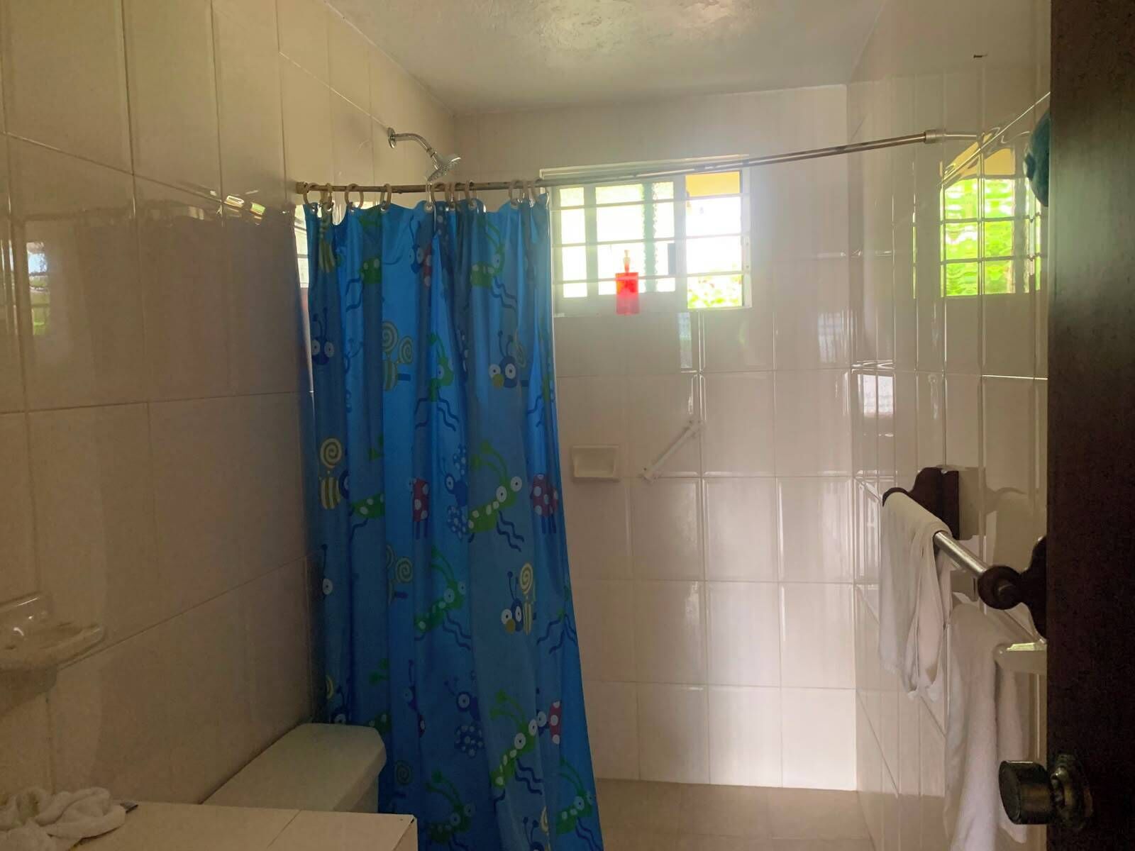A bathroom with a shower curtain, a toilet, and a bathtub.
