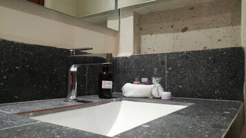 A bathroom with a granite countertop, a white sink, a mirror, and a towel rack.