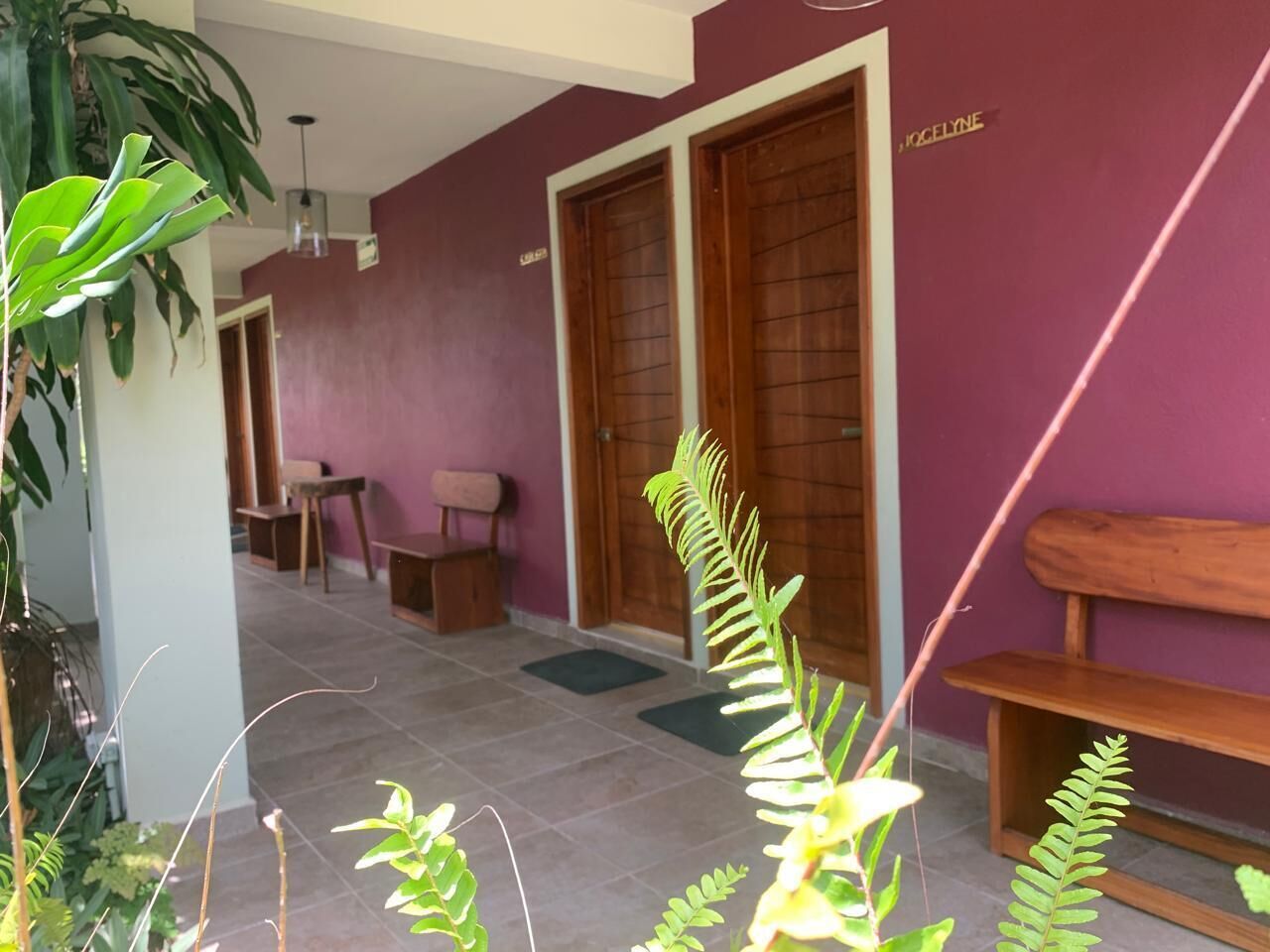 Una habitación con una pared morada, un banco de madera y una puerta con la leyenda 'JOSELYNE'.