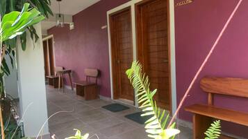 Una habitación con una pared morada, un banco de madera y una puerta con la leyenda 'JOSELYNE'.