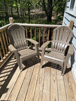 Eine Holzterrasse mit zwei Adirondack-Stühlen und einem Hollerker.