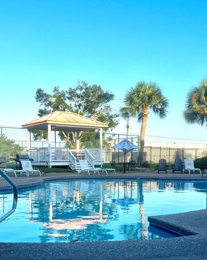 A swimming pool with lounge chairs and a gazebo.